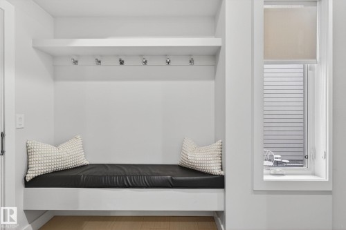 Built-in mudroom bench featuring a black cushion, overhead shelving, and multiple coat hooks - 1313 Hainstock Way Sw, Edmonton, AB - Indoor