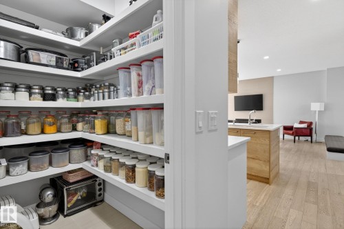 Corner pantry with extensive white shelving, providing ample storage - 1313 Hainstock Way Sw, Edmonton, AB - Indoor