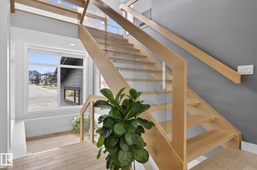 Modern staircase featuring light wood-finish treads and handrails - 1313 Hainstock Way Sw, Edmonton, AB - Indoor Photo Showing Other Room