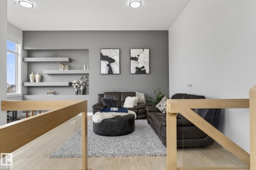 Open concept living area featuring light wood-finish flooring, a contemporary floating shelf unit, and recessed wall art niches - 1313 Hainstock Way Sw, Edmonton, AB - Indoor