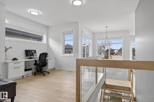 Bright open loft space featuring light wood-finish flooring and multiple windows for abundant illumination - 1313 Hainstock Way Sw, Edmonton, AB - Indoor