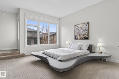 Carpeted bedroom featuring large windows, white trim, and light-colored walls - 1313 Hainstock Way Sw, Edmonton, AB - Indoor Photo Showing Bedroom
