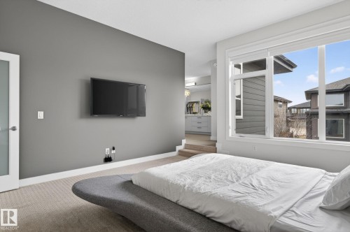 Carpeted room with a large window featuring white framing and trim - 1313 Hainstock Way Sw, Edmonton, AB - Indoor Photo Showing Bedroom