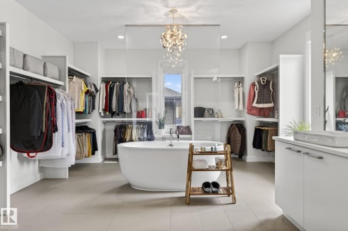 Spacious dressing room featuring a freestanding soaking tub, extensive built-in shelving, ample wardrobe hanging space, and a modern vanity with a vessel sink - 1313 Hainstock Way Sw, Edmonton, AB - Indoor