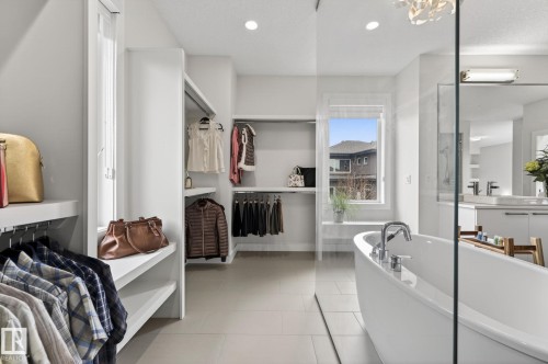 Freestanding soaking tub with chrome fixtures, glass shower enclosure, integrated shelving, and recessed lighting - 1313 Hainstock Way Sw, Edmonton, AB - Indoor Photo Showing Bathroom