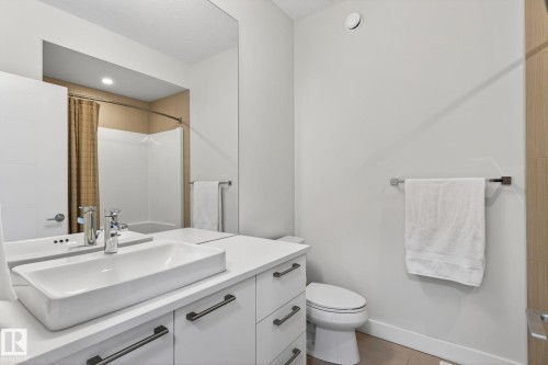 Contemporary bathroom featuring a rectangular vessel sink, white vanity with matte black hardware, large wall-mounted mirror, and a full-size bathtub with shower - 1313 Hainstock Way Sw, Edmonton, AB - Indoor Photo Showing Bathroom
