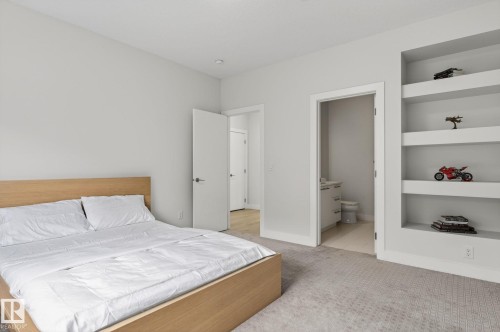 Bedroom featuring light neutral tone walls, patterned carpet flooring, recessed lighting, and built-in shelving - 1313 Hainstock Way Sw, Edmonton, AB - Indoor Photo Showing Bedroom
