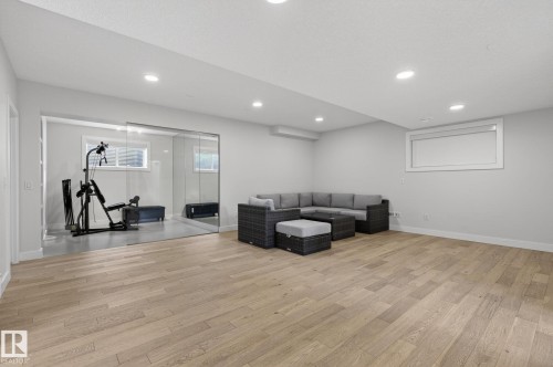Spacious room featuring light wood-finish flooring, recessed lighting, and a neutral wall palette - 1313 Hainstock Way Sw, Edmonton, AB - Indoor