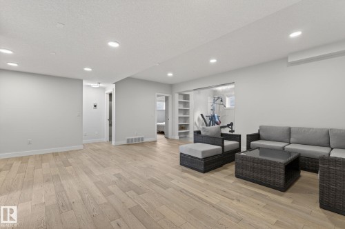 Spacious lower-level area featuring recessed lighting, light wood-finish flooring, and white painted walls - 1313 Hainstock Way Sw, Edmonton, AB - Indoor
