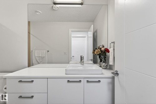 Bathroom vanity featuring a rectangular vessel sink, polished chrome faucet, and expansive wall-mounted mirror - 1313 Hainstock Way Sw, Edmonton, AB - Indoor Photo Showing Bathroom