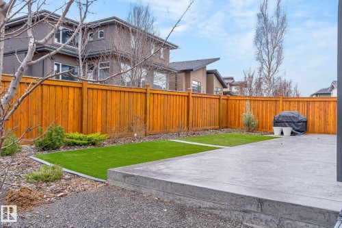 Private backyard featuring a concrete patio, artificial turf sections, and a wood privacy fence - 1313 Hainstock Way Sw, Edmonton, AB - Outdoor