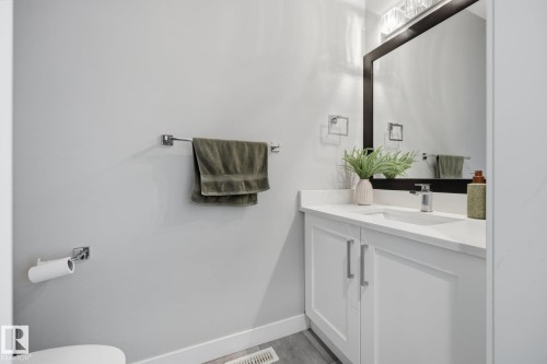 Bathroom vanity featuring white cabinetry, a white countertop with an integrated sink, and a chrome faucet  MAIN FLOOR HALF BATH - 3870 Robins Crescent Nw, Edmonton, AB - Indoor Photo Showing Bathroom