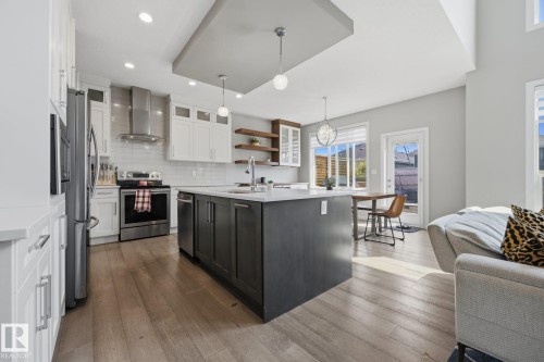 Open-concept kitchen featuring an oversized island, stainless steel appliances, wood-finish flooring, white subway tile backsplash, and recessed and pendant lighting - 3870 Robins Crescent Nw, Edmonton, AB - Indoor Photo Showing Kitchen With Upgraded Kitchen