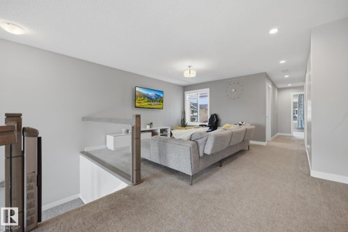 Upper-level landing featuring neutral carpeting, a wood-finish railing with metal accents, and recessed ceiling lighting - 3870 Robins Crescent Nw, Edmonton, AB - Indoor