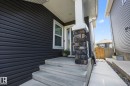 Front entry featuring a stone-clad column, concrete steps, and dark horizontal siding - 3870 Robins Crescent Nw, Edmonton, AB  - Outdoor With Exterior 