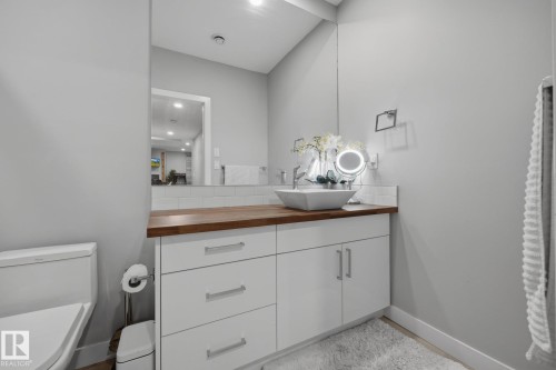 Bathroom vanity with a vessel sink, wood-finish countertop, white cabinetry, and subway tile backsplash - 3870 Robins Crescent Nw, Edmonton, AB - Indoor Photo Showing Bathroom