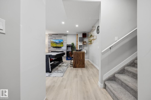 Lower level entertainment space featuring light wood-finish flooring, recessed lighting, and a textured accent wall - 3870 Robins Crescent Nw, Edmonton, AB - Indoor Photo Showing Other Room