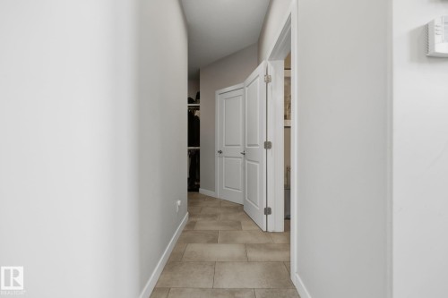 Hallway featuring tile flooring, neutral wall paint, white baseboards, and a white bi-fold door - 3870 Robins Crescent Nw, Edmonton, AB - Indoor Photo Showing Other Room