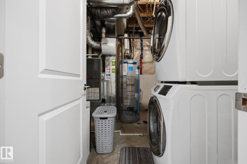 Dedicated utility area featuring a stackable washer and dryer, water heater, and furnace - 3870 Robins Crescent Nw, Edmonton, AB - Indoor Photo Showing Laundry Room