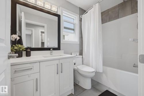 Bathroom featuring a white vanity with an integrated sink, a dark framed mirror, and chrome hardware - 3870 Robins Crescent Nw, Edmonton, AB - Indoor Photo Showing Bathroom