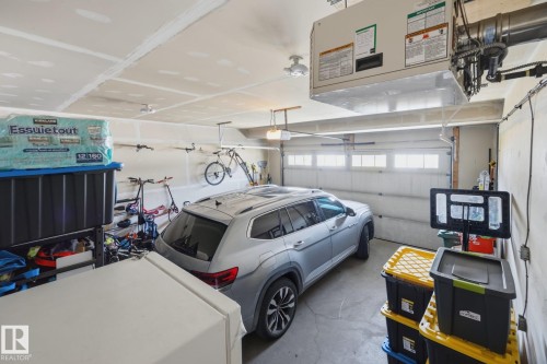 Attached garage with concrete flooring, overhead lighting, and a white panel garage door featuring transom windows - 3870 Robins Crescent Nw, Edmonton, AB - Indoor Photo Showing Garage