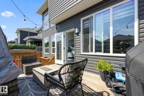 Rear exterior featuring dark gray horizontal siding, a light wood-finish deck with railing, and a large sliding glass door - 3870 Robins Crescent Nw, Edmonton, AB - Outdoor With Deck Patio Veranda With Exterior