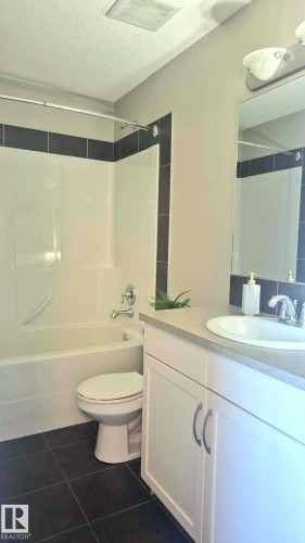 Bathroom featuring dark tile flooring, a white vanity with a light-colored countertop, and an integrated sink - 225 51A Street Sw, Edmonton, AB - Indoor Photo Showing Bathroom
