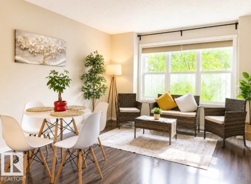 Open-concept living area featuring wood-finish flooring, a multi-pane window with roller blinds, and neutral wall tones - 225 51A Street Sw, Edmonton, AB - Indoor