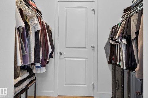 Walk-in closet with white paneled door, wood-finish flooring, and integrated wire shelving - #203 5521 7 Av Sw, Edmonton, AB - Indoor With Storage