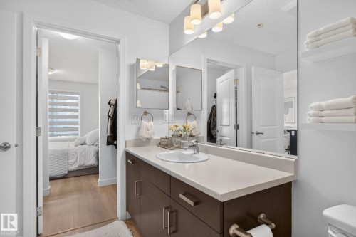 Bathroom vanity featuring a light-toned countertop, undermount sink, and dark wood-finish cabinetry - #203 5521 7 Av Sw, Edmonton, AB - Indoor Photo Showing Bathroom