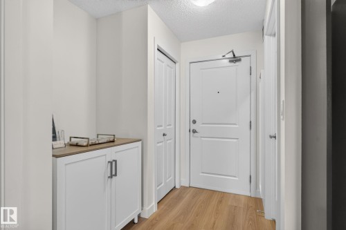 Entryway featuring wood-finish flooring, a white paneled door, and built-in closet storage - #203 5521 7 Av Sw, Edmonton, AB - Indoor Photo Showing Other Room