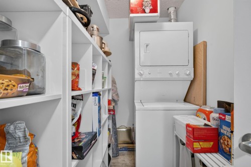 White built-in shelving with cubbies and a stacked washer and dryer unit - #203 5521 7 Av Sw, Edmonton, AB - Indoor Photo Showing Laundry Room
