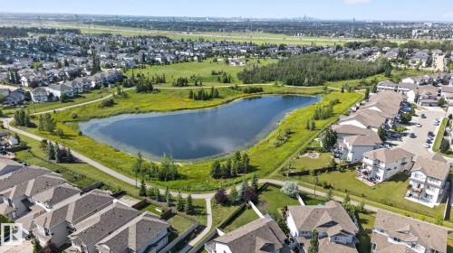 Aerial perspective showcasing a residential area with a prominent central pond - #203 5521 7 Av Sw, Edmonton, AB - Outdoor With View