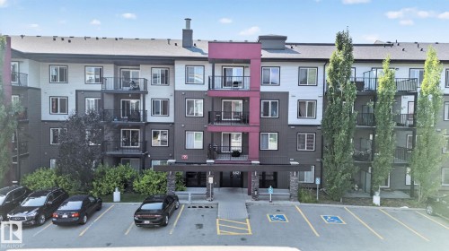 Modern multi-story building featuring a facade with white, charcoal, and magenta paneling - #203 5521 7 Av Sw, Edmonton, AB - Outdoor With Balcony With Facade