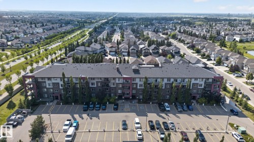 Multi-story residential building with contemporary siding and balcony features, surrounded by mature landscaping - #203 5521 7 Av Sw, Edmonton, AB - Outdoor With View