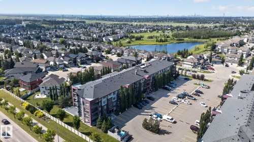 Modern multi-story building featuring balconies, a parking lot, and mature trees - #203 5521 7 Av Sw, Edmonton, AB - Outdoor With View