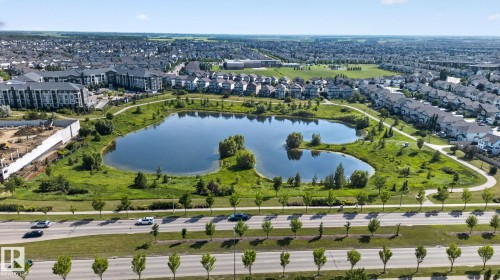 Expansive neighborhood featuring a large central pond with surrounding green spaces and walking paths - #203 5521 7 Av Sw, Edmonton, AB - Outdoor With Body Of Water With View