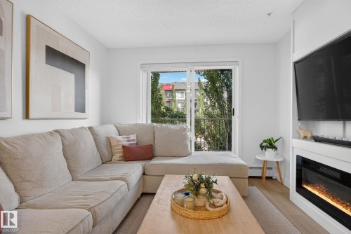 Living area featuring wood-finish flooring, white walls, and a built-in electric fireplace - #203 5521 7 Av Sw, Edmonton, AB - Indoor Photo Showing Living Room With Fireplace