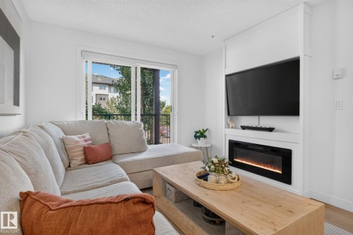 Living area with a built-in media center featuring an electric fireplace - #203 5521 7 Av Sw, Edmonton, AB - Indoor Photo Showing Living Room With Fireplace