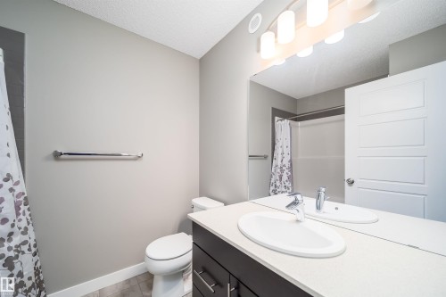 Bathroom featuring a dark wood-finish vanity with a white countertop, an oval undermount sink, and a chrome faucet - 114 James Crescent, St. Albert, AB - Indoor Photo Showing Bathroom