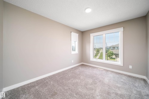 Carpeted room featuring neutral-toned walls, white trim, and a large window with white framing - 114 James Crescent, St. Albert, AB - Indoor Photo Showing Other Room