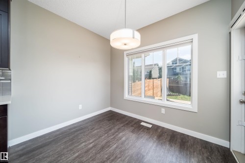 Bright dining space featuring a contemporary ceiling fixture, large window, wood-finish flooring, and light gray walls - 114 James Crescent, St. Albert, AB - Indoor Photo Showing Other Room