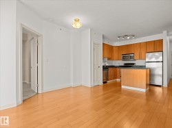 Open-concept kitchen featuring wood-finish cabinetry, stainless steel appliances, dark countertops, and a central island - 