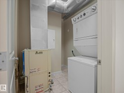 Dedicated laundry area featuring a white stacked washer and dryer unit, ceramic tile flooring, and exposed galvanized ductwork - 