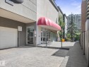 Building exterior featuring a red fabric awning, floor-to-ceiling glass storefront, and a concrete paver entrance - #707 9819 104 St Nw, Edmonton, AB  - Outdoor With Exterior 