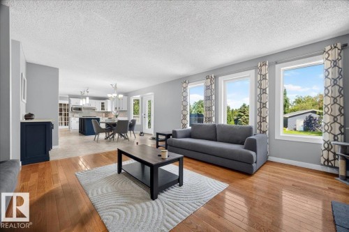 Living space featuring wood-finish flooring, light grey wall paint, and multiple large windows - #47 21061 Wye Rd, Rural Strathcona County, AB - Indoor Photo Showing Living Room