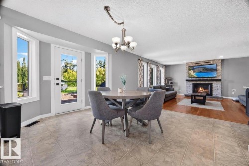 Open-concept living space with a stone-surround fireplace, a built-in mantel, and recessed lighting - #47 21061 Wye Rd, Rural Strathcona County, AB - Indoor Photo Showing Dining Room With Fireplace