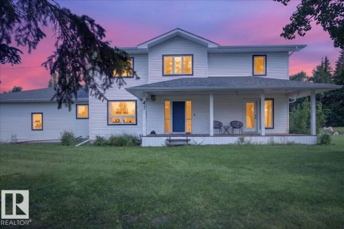 Exterior featuring white horizontal siding, a covered porch with white columns, a dark blue entry door, and multiple windows with dark trim - #47 21061 Wye Rd, Rural Strathcona County, AB - Outdoor With Deck Patio Veranda