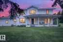Exterior featuring white horizontal siding, a covered porch with white columns, a dark blue entry door, and multiple windows with dark trim - #47 21061 Wye Rd, Rural Strathcona County, AB  - Outdoor With Deck Patio Veranda 