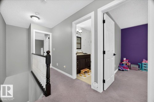 Second-story hallway featuring a white spindle railing with a dark wood newel post, light gray wall finishes, and textured ceiling - #47 21061 Wye Rd, Rural Strathcona County, AB - Indoor Photo Showing Other Room